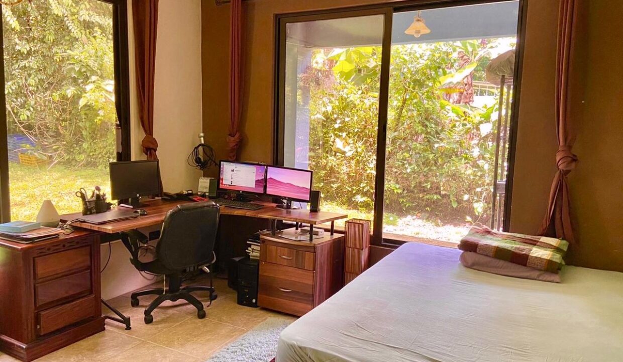 Bedroom with dual-monitor office setup and lush garden views – La Fortuna Costa Rica Real Estate