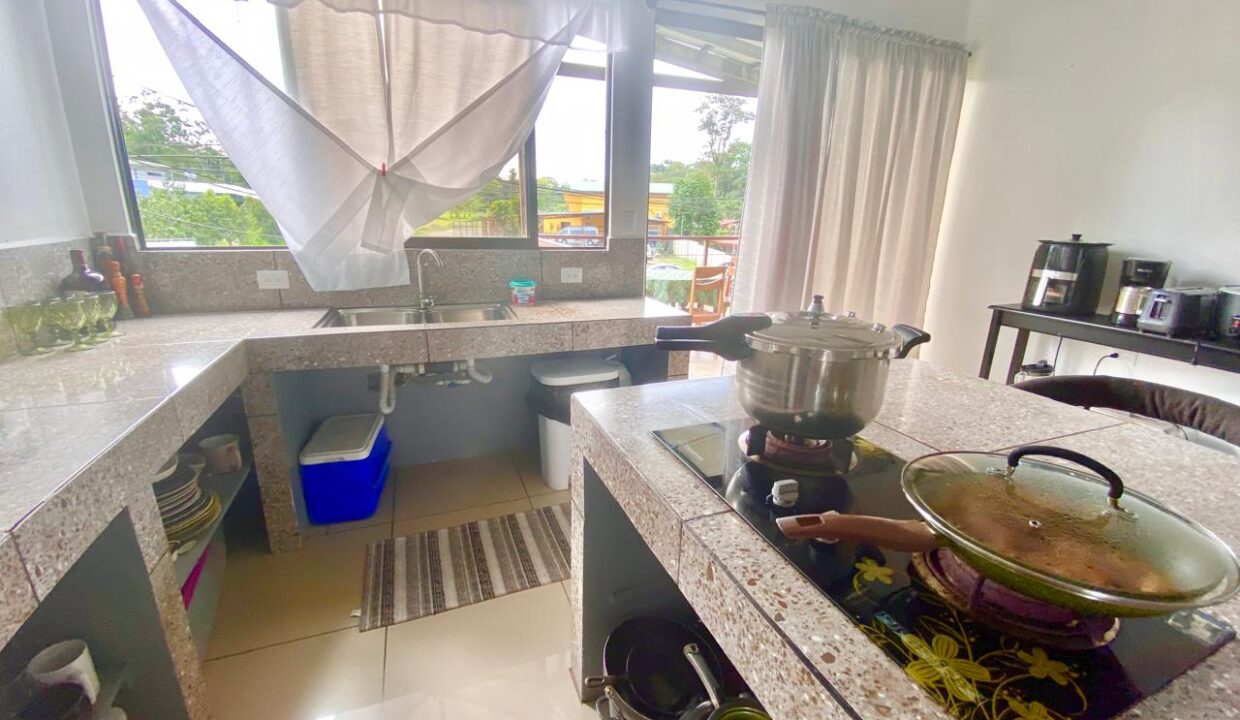 Spacious upper-level kitchen with open layout and terrace access in La Fortuna home