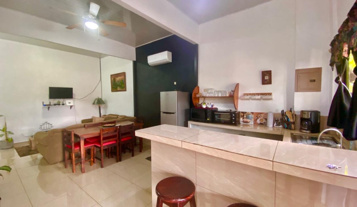 Furnished ground-floor unit with open-concept kitchen, lounge area, and TV in La Fortuna
