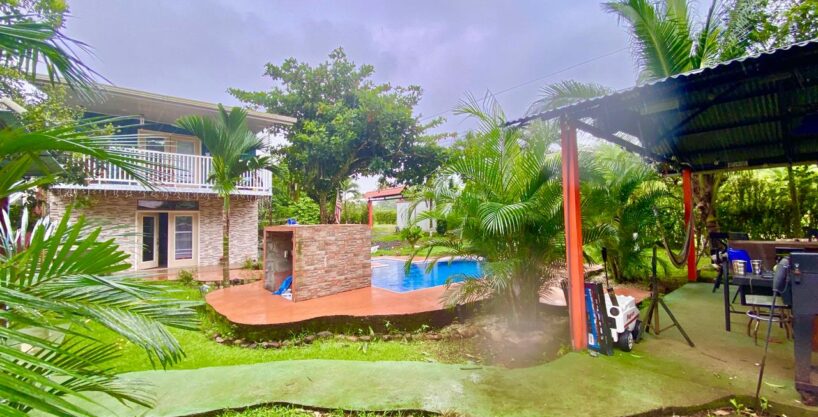 overview of duplex, pool with waterfall, and BBQ rancho under palm trees