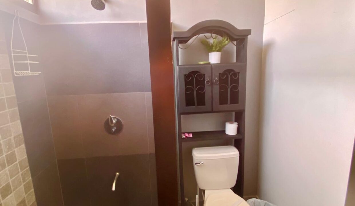 Modern tiled bathroom with enclosed shower and toilet in La Fortuna Airbnb rental