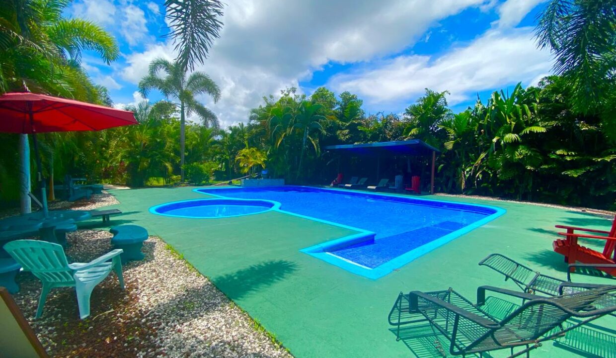 Resort-style pool with lounge chairs and umbrellas in La Fortuna Costa Rica real estate near Arenal Volcano