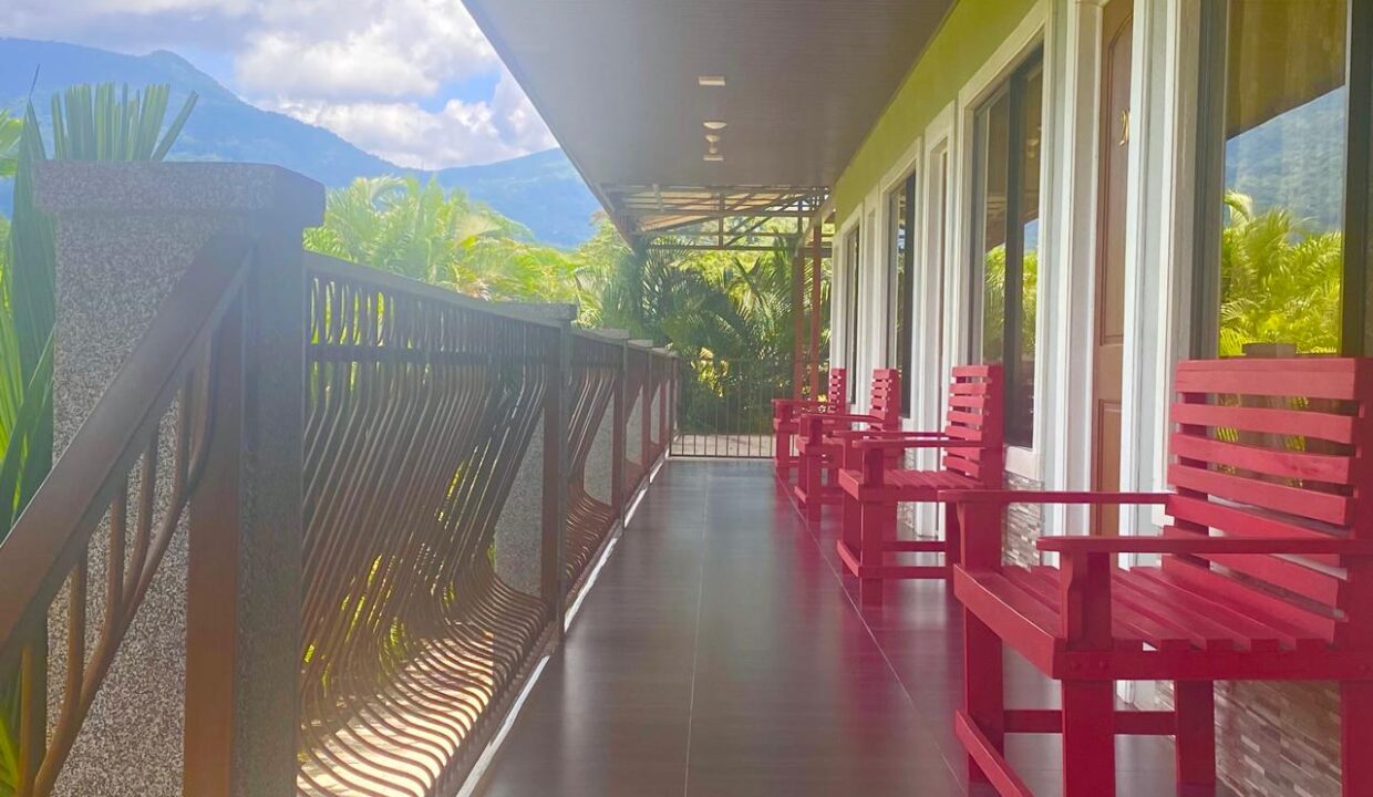 Front view of hotel exterior with columns and red chairs in La Fortuna, Costa Rica