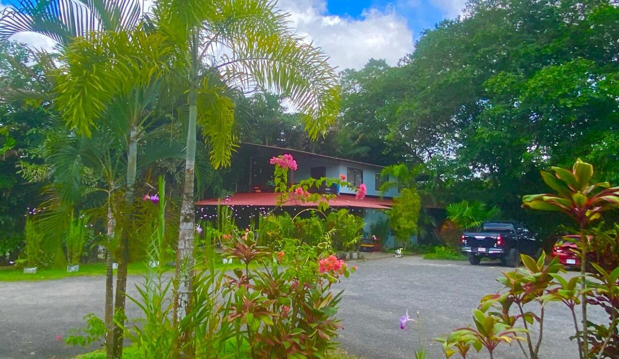 Two-story building with tropical plants and red roof in central La Fortuna Costa Rica real estate near Arenal Volcano by Tropical Glow