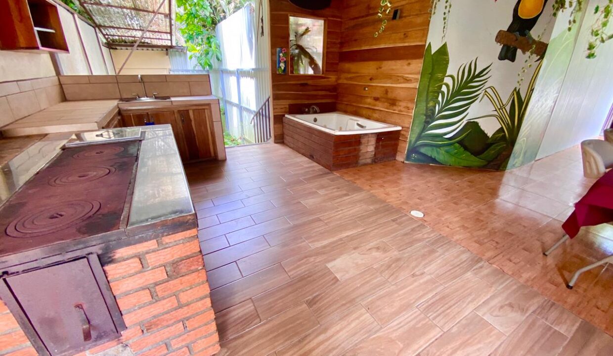 Rustic lounge area featuring a wood-paneled pavilion, spa tub, and vibrant toucan mural in a Jauuri rental home