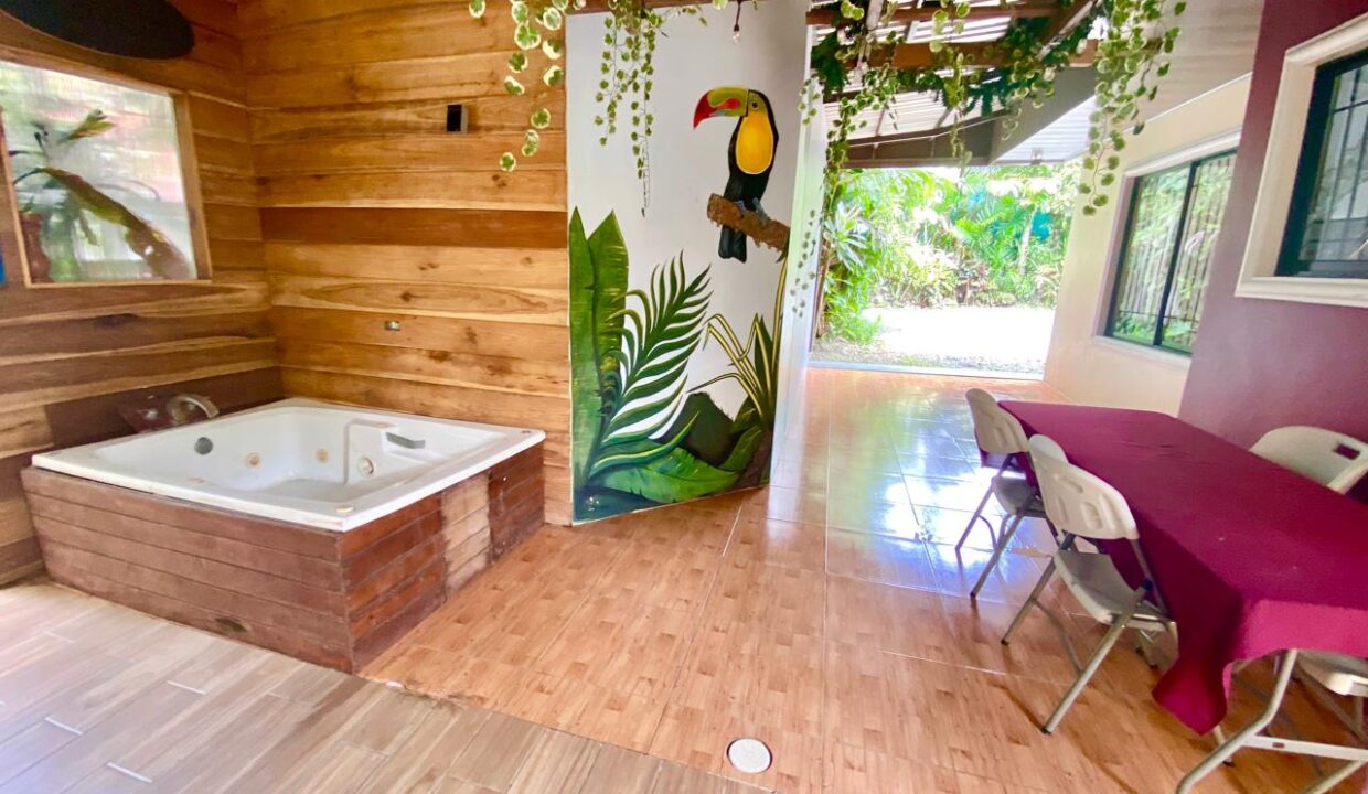 Brick‑front outdoor kitchen with tiled floor, sink, and spa tub at La Fortuna Costa Rica Airbnb investment near Arenal Volcano