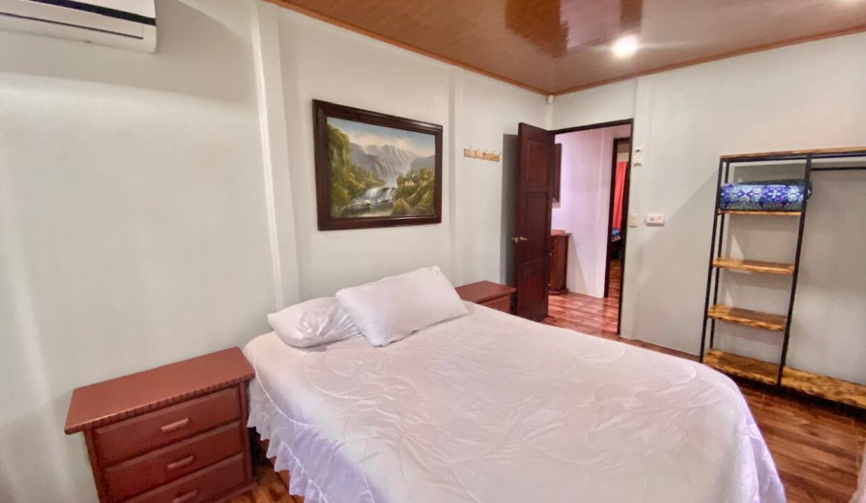 Spacious and bright bedroom with framed artwork and wooden furnishings