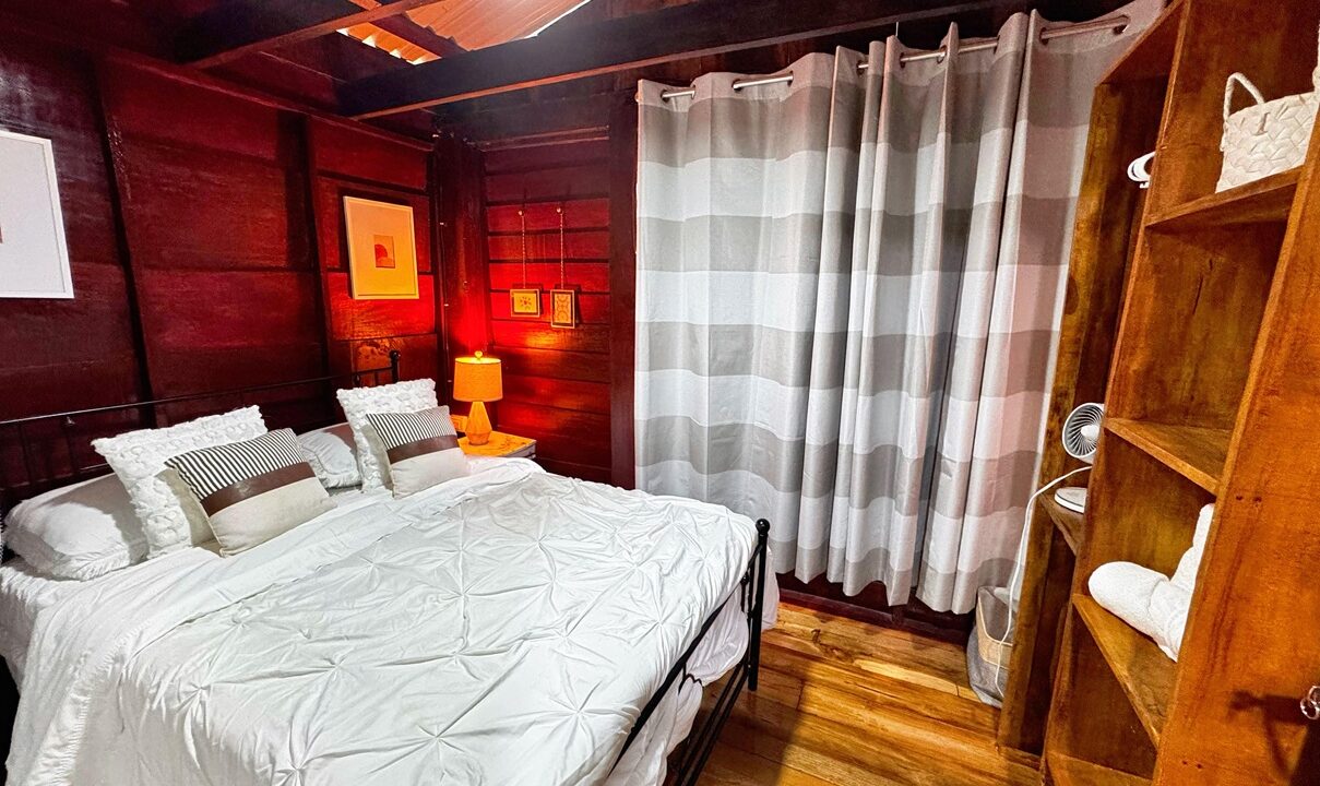 Costa Rica property with large furnished bedroom and warm lighting near Arenal Volcano. La Fortuna real estate investment with natural surroundings.