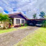 Tropical Glow Cozy single-story home surrounded by lush greenery palm trees and a clear blue sky offering a serene living environment in La Fortuna Costa Rica Real Estate